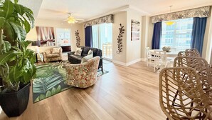 Un salon spacieux avec un canapé en cuir, un fauteuil à motifs floraux et un coin repas doté de chaises en osier.