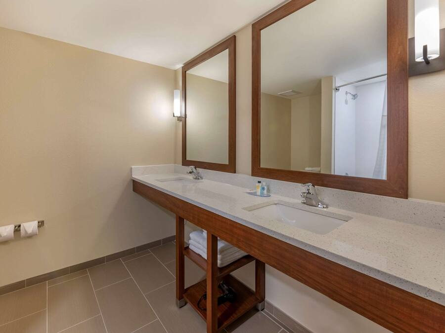 A bathroom with two sinks, a large mirror, and a towel rack.