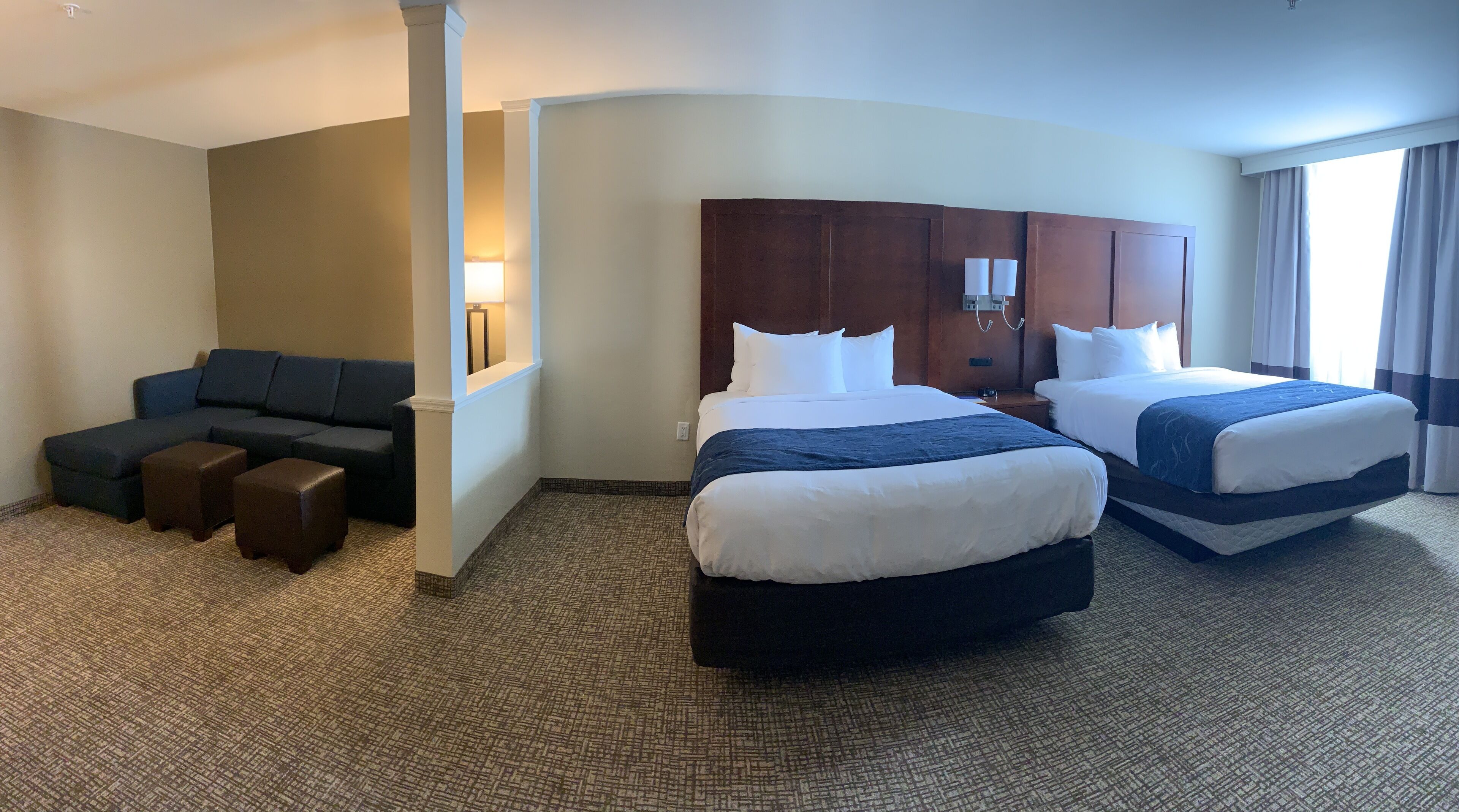 A hotel room with two beds, a sofa, and a small seating area.