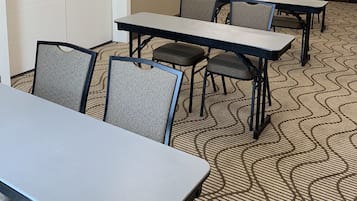 A conference room with tables and chairs, a door, and a patterned carpet.