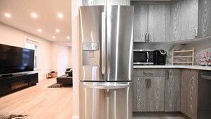 Una cocina moderna con un refrigerador de acero inoxidable grande, armarios de madera y un televisor de pantalla plana.