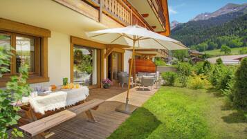 Une terrasse en bois avec des meubles d’extérieur, un patio couvert et une vue sur un paysage montagneux.