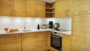 Una cocina moderna con gabinetes de madera, un lavamanos de acero inoxidable, un tostador, una cafetera y un horno.