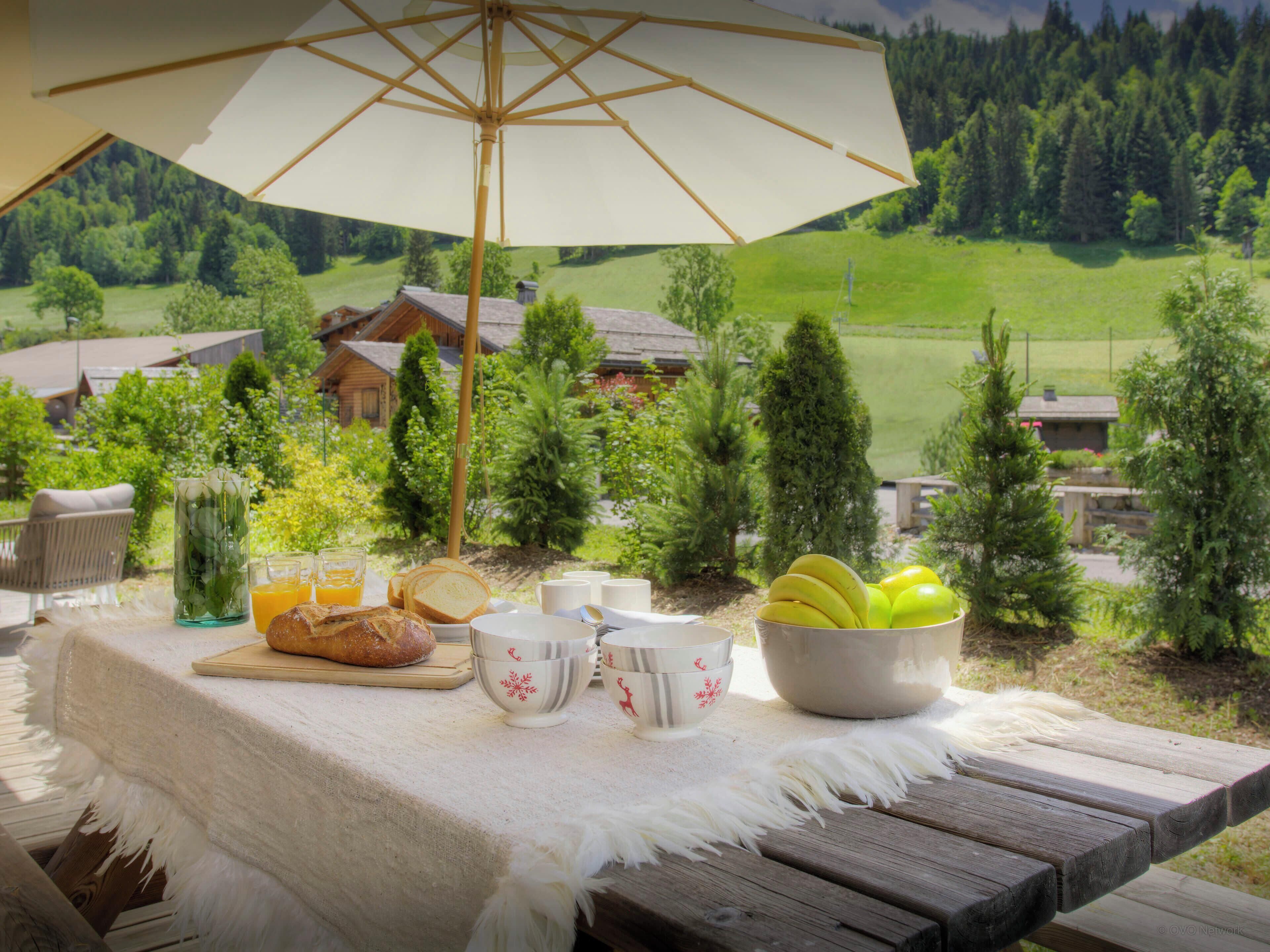 Une table de pique-nique installée à l’extérieur, offrant une vue sur un paysage rural, avec des maisons et des arbres.