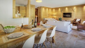 Un comedor moderno con una mesa de madera, sillas blancas y una araña.