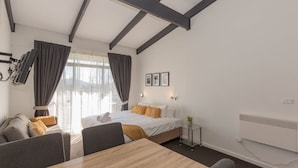 Et hotelværelse med en seng, et skrivebord, en stol, et lille bord og en radiator.