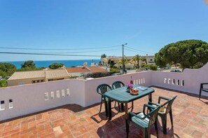 A terrace with a table and chairs, overlooking a coastal area with buildings and trees. - Nice 4-bedroom villa in Carvoeiro, by the sea (Carvoeiro)