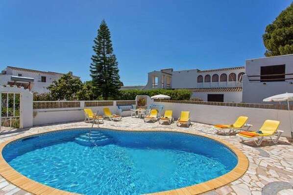 A swimming pool with lounge chairs, surrounded by a stone deck and white buildings with arches. - Nice 4-bedroom villa in Carvoeiro, by the sea (Carvoeiro)