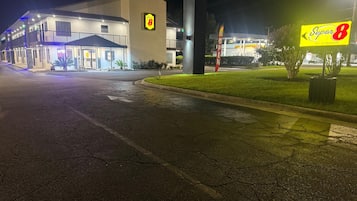 A Super 8 hotel with a large sign, a parking lot, and a well-lit entrance.