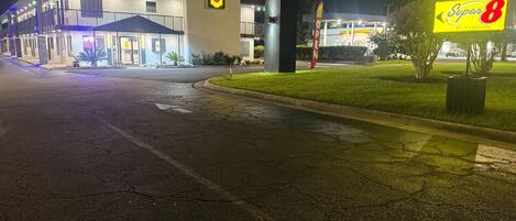A Super 8 hotel with a large sign, a parking lot, and a well-lit entrance.