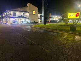 Un hotel Super 8 con un cartel grande, un estacionamiento y una entrada bien iluminada.