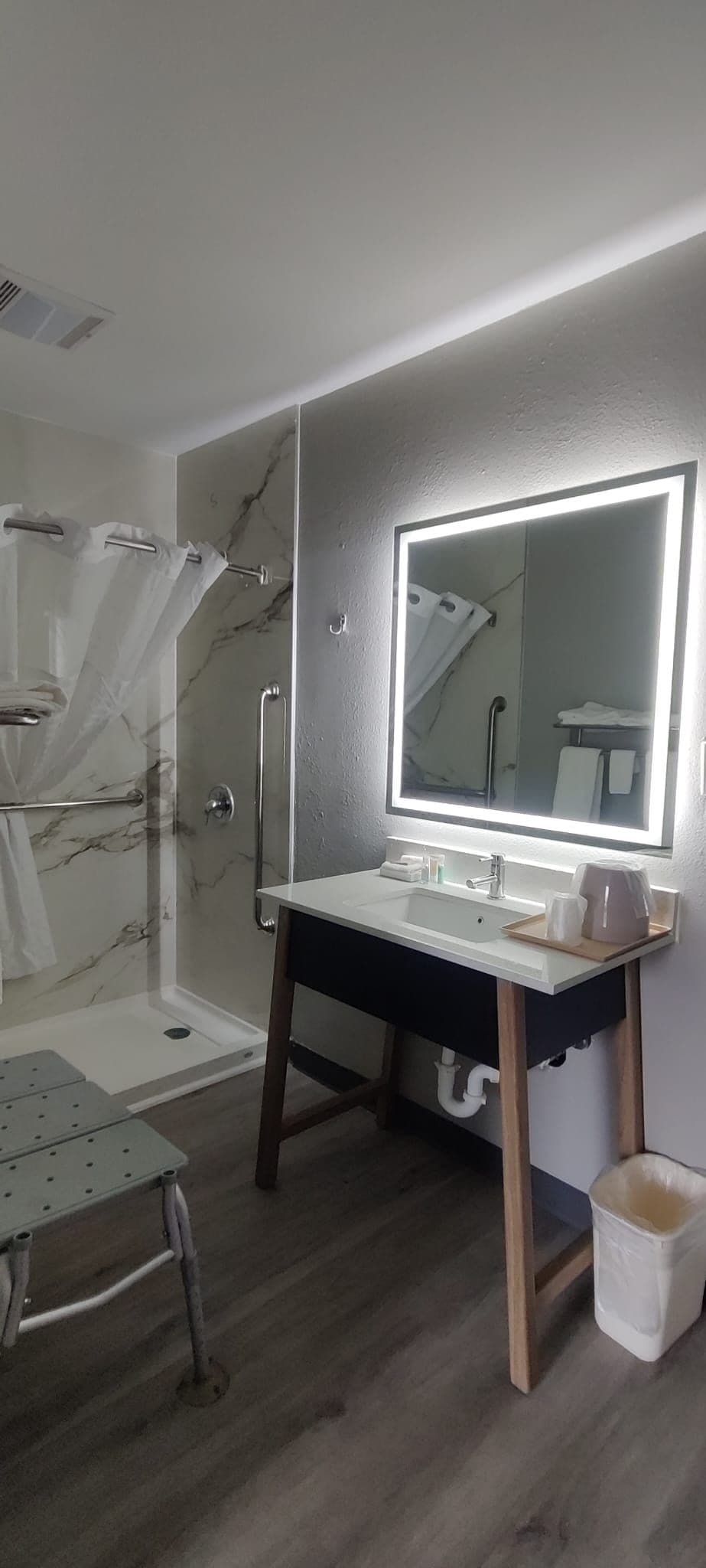 A bathroom with a marble shower, a vanity with a mirror, and a toilet.