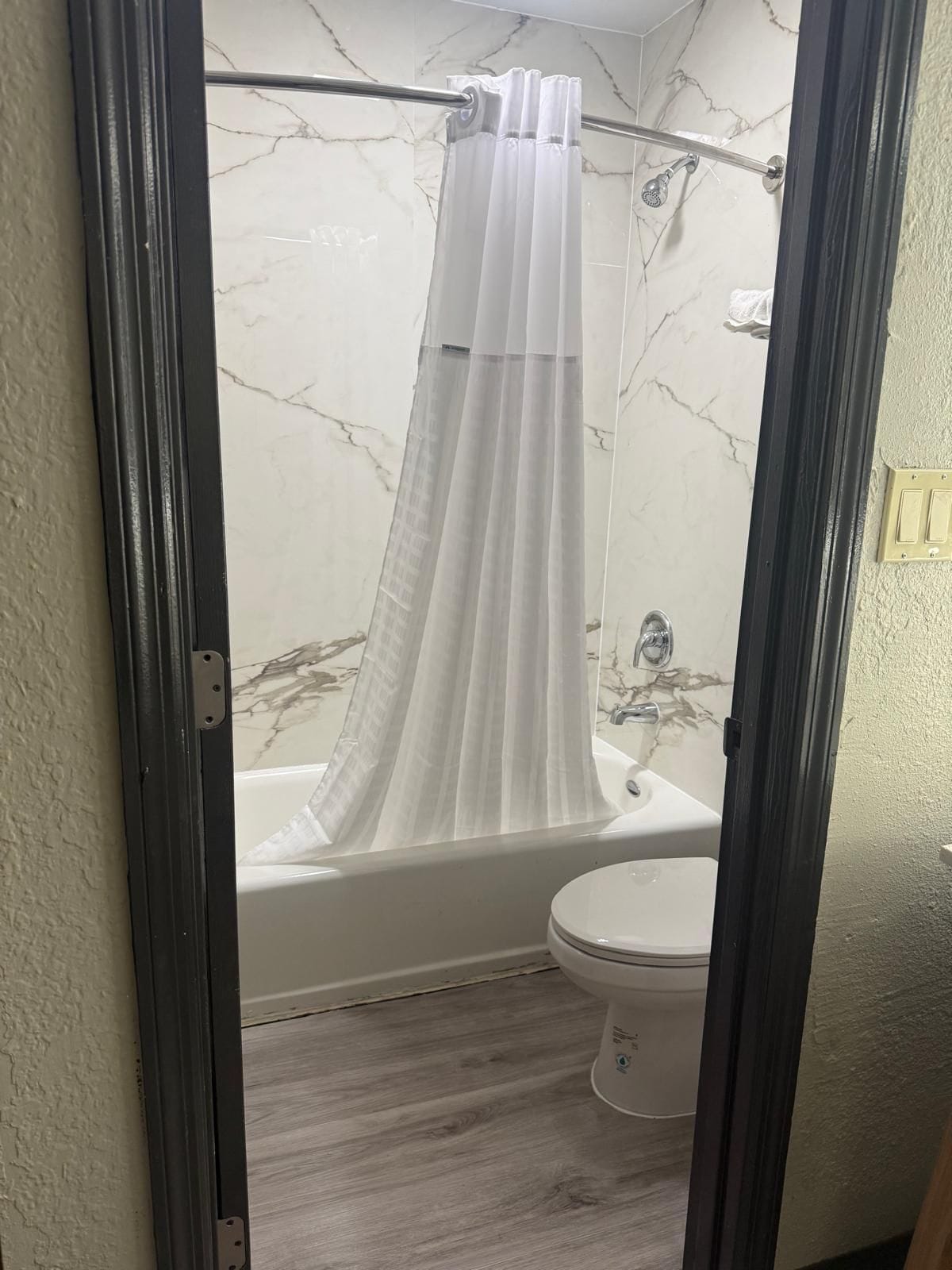 A bathroom with a bathtub, toilet, and shower curtain.