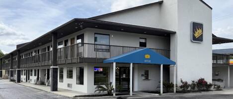A hotel with a blue awning, a sign indicating it's open, and a crown logo on the building.