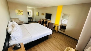 Une chambre d’hôtel équipée d’un lit, d’un bureau, d’une chaise, d’une télévision et d’un miroir.