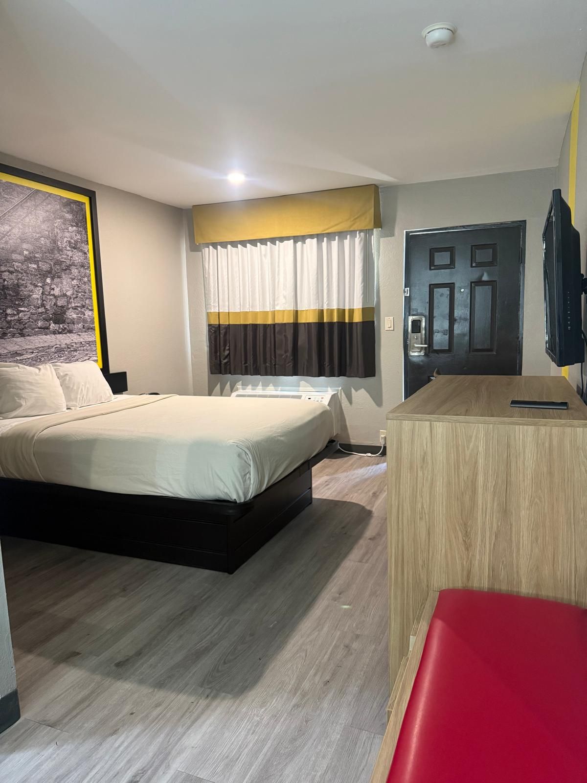 Una camera d'albergo con un letto, una scrivania, un televisore e una porta.