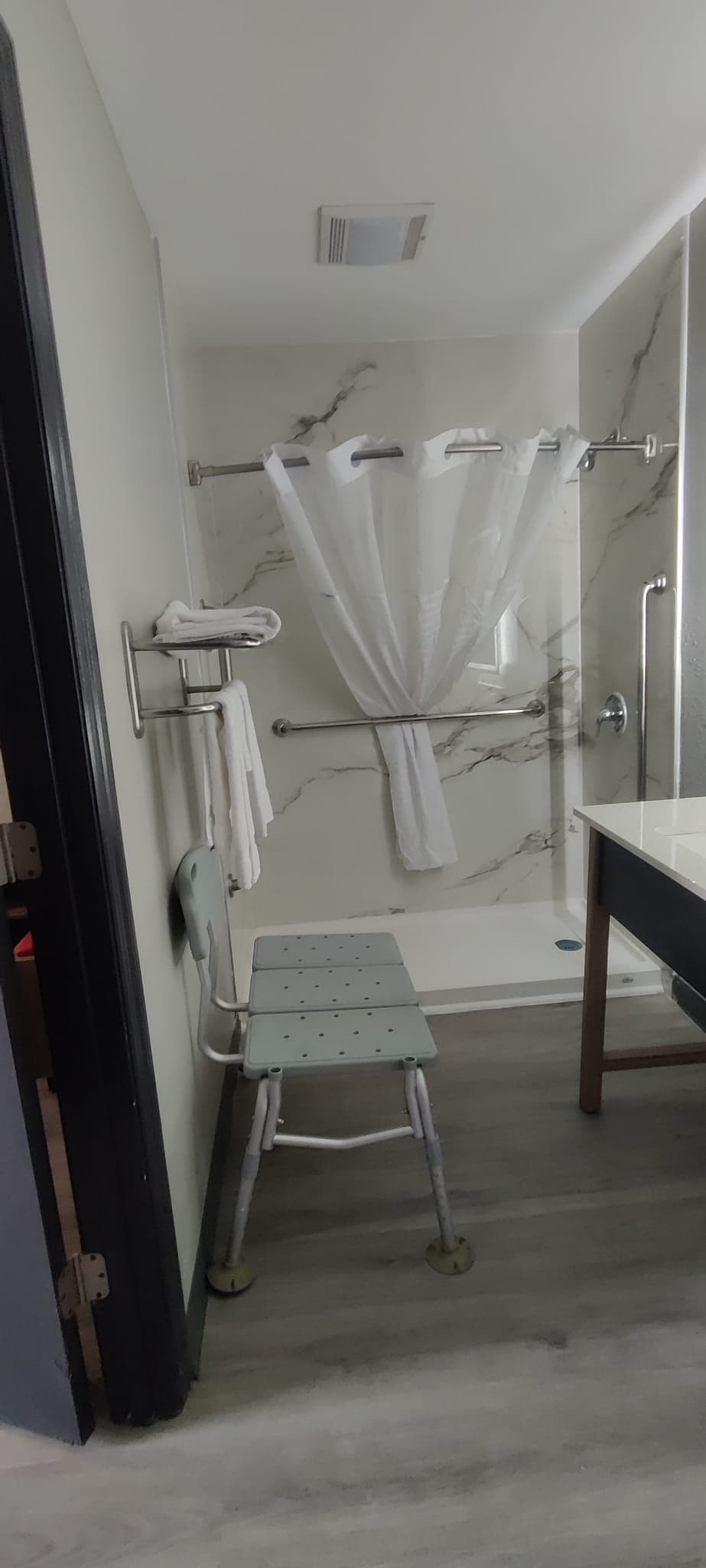 A bathroom with a shower, a towel rack, and a sink.