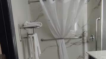 A bathroom with a shower, a towel rack, and a sink.