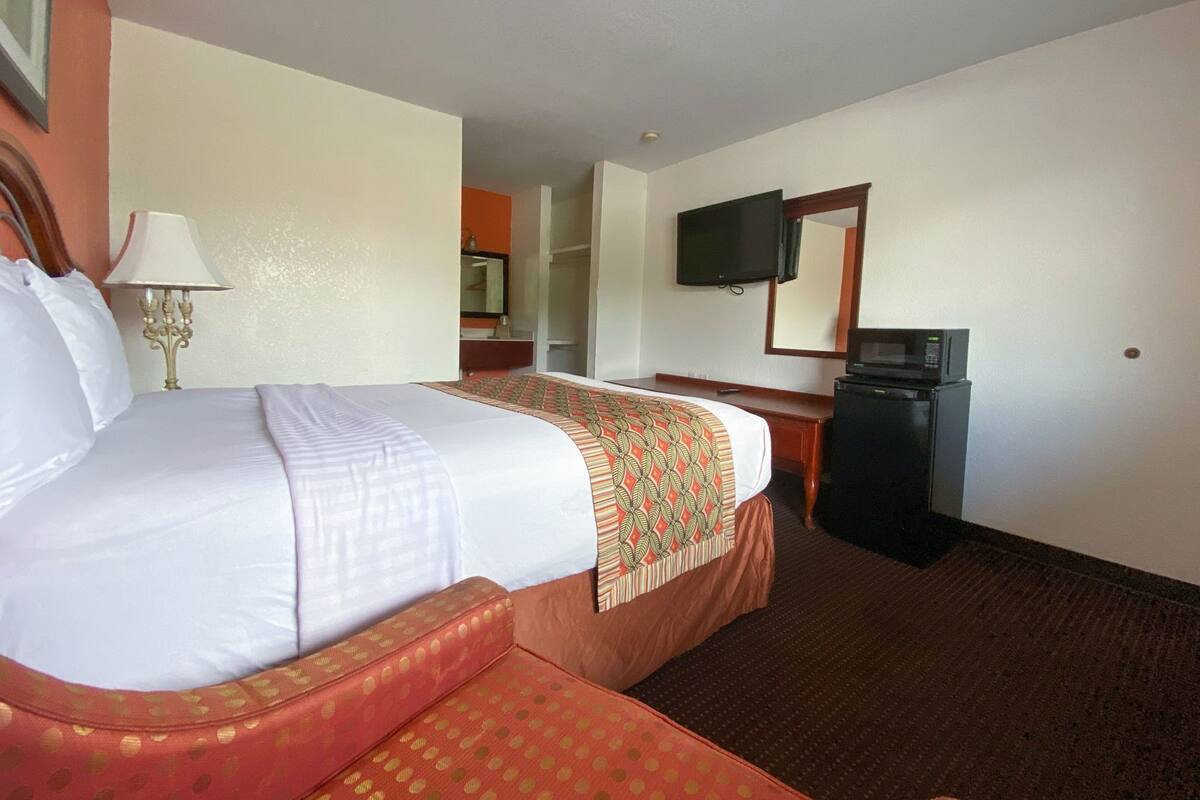 A hotel room with a bed, a desk, a television, and a microwave.