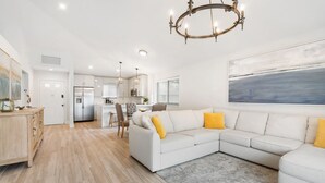 A modern living room with a sectional sofa, a dining area, and a kitchen. - Private Cottage at PGA National (Palm Beach Gardens)