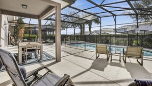 A covered outdoor area with a pool, seating, and a view of the surrounding neighborhood. - ✨ Luxurious 6BR Villa with Private Pool & Game Room near Disney 🏊‍♂️🎮 (Davenport)