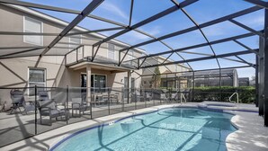 An indoor swimming pool with clear glass walls, surrounded by lounge chairs and a covered patio area. - ✨ Luxurious 6BR Villa with Private Pool & Game Room near Disney 🏊‍♂️🎮 (Davenport)