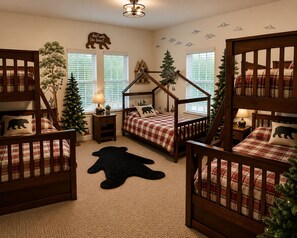 A cozy bedroom with two wooden bunk beds, a nightstand with a lamp, a Christmas tree, and wall decals.