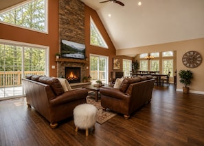 A spacious living room with a fireplace, leather sofas, a dining area, and large windows. - Luxury Chalet Masthope Near Narrowsburg & Delaware (Masthope)