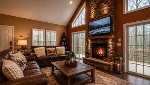 Una sala de estar con chimenea de piedra, sofá de cuero y ventanas grandes.