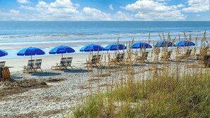 Una playa con sombrillas azules y sillas de playa.