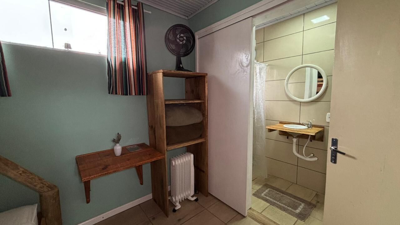Une salle de bain avec un radiateur, une étagère en bois, un miroir et un lavabo.