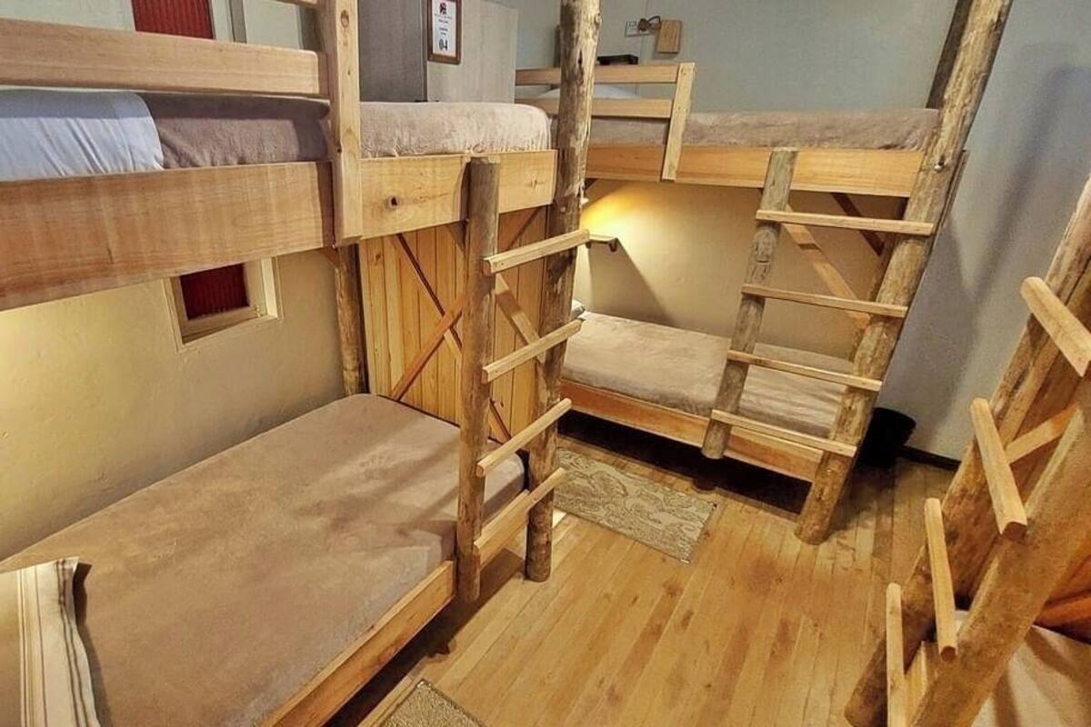 A bunk bed room with wooden ladders and a small window.
