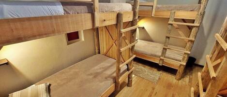 A bunk bed room with wooden ladders and a small window.