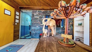 Una habitación con techo de madera, una pared con pizarrón y escrituras, una escultura de madera de elefante, y un letrero que dice “MARAUARIA”.