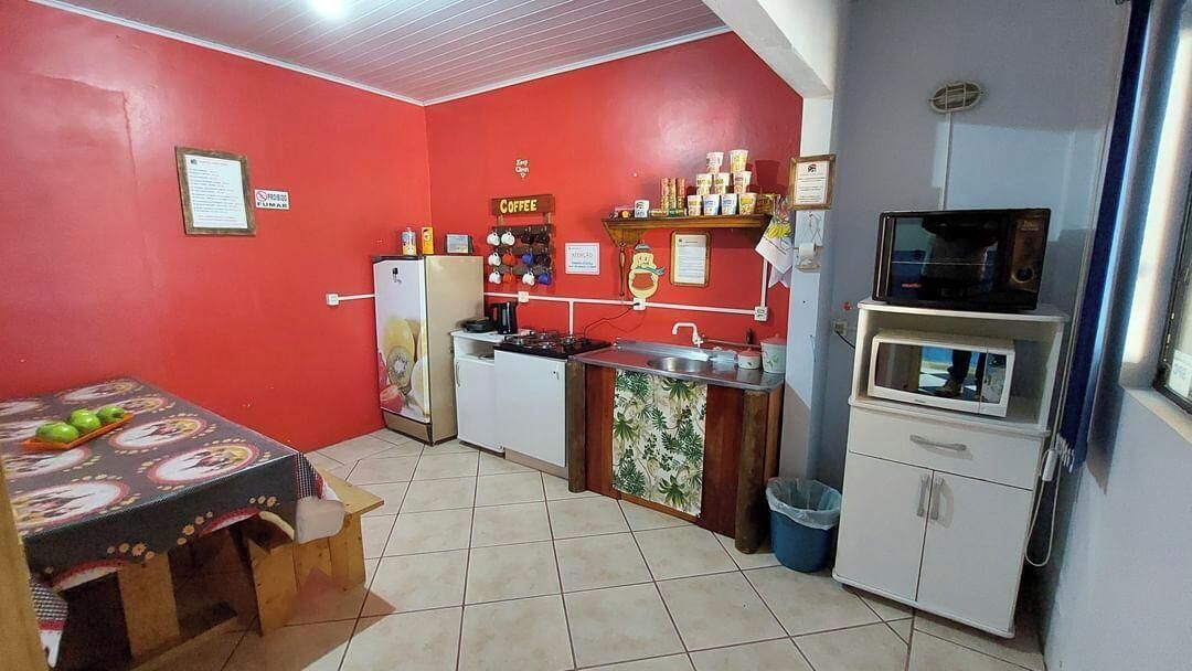 Une cuisine compacte aux murs rouges, équipée d’un coin café, d’un four à micro-ondes et d’un petit réfrigérateur.