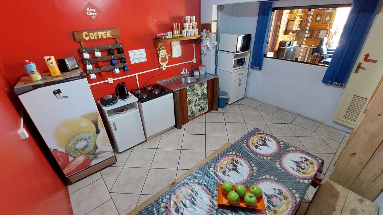 Une cuisine compacte équipée d’un coin café, d’un réfrigérateur, d’une cuisinière et d’une table à manger agrémentée d’un panier de fruits.