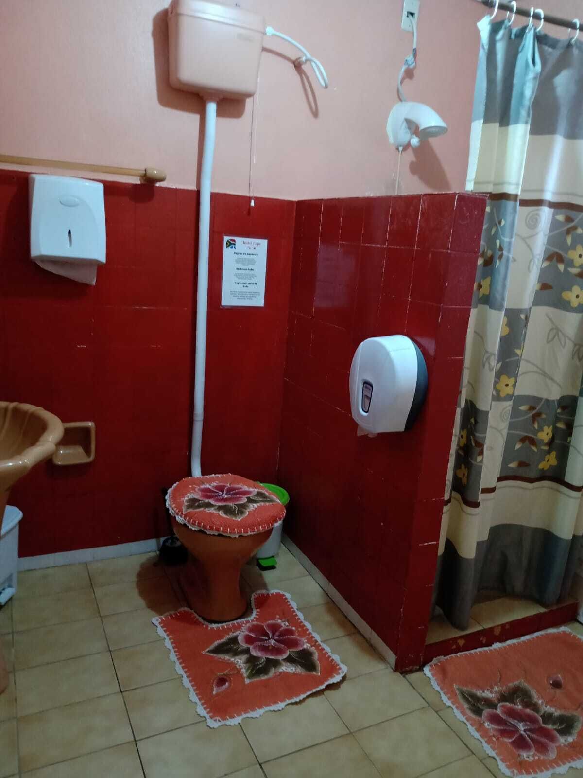 Une salle de bain équipée de toilettes, d’un sèche-mains, d’un distributeur d’essuie-tout, d’un distributeur de savon liquide et d’un rideau de douche.