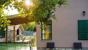 A patio area with a stone wall, a wooden pergola, and a table with chairs. - Villa G&P (ST) - Two-Bedroom Villa with Private Pool (Trilj)