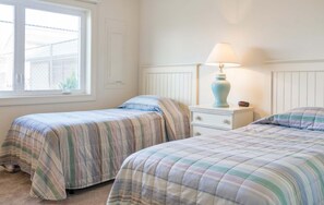 Una camera da letto con due letti, un comodino, una lampada e una finestra.