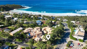 Vue aérienne d’une zone résidentielle côtière, avec des maisons, une route et une plage.