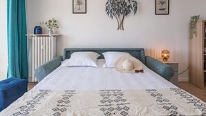 Een slaapkamer met een bed, nachtkastje met lamp, radiator en raam met gordijnen.