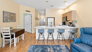Una cucina moderna con isola centrale, sgabelli da bar, un tavolo da pranzo con sedie e un divano blu.