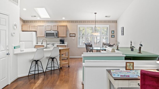 Una cucina compatta con elettrodomestici moderni, una zona pranzo con un tavolo verde e un gioco dell'opoly su un tavolo.