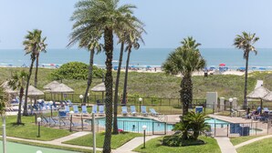 A resort with a pool, beach, and palm trees.