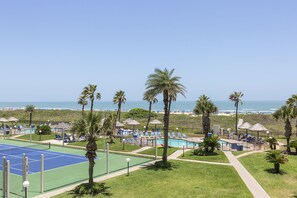 Ein Strandresort mit Tennisplatz, Poolbereich und Liegestühlen.