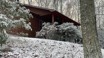 Una baita con tetto spiovente, immersa tra alberi innevati.
