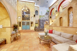 A spacious lobby with a large sofa, a coffee table, and a decorative fountain.