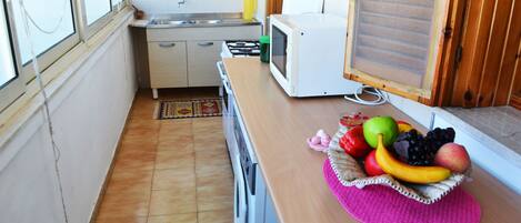 Een koelkast, een oven, een kookplaat, kookgerei, borden en bestek