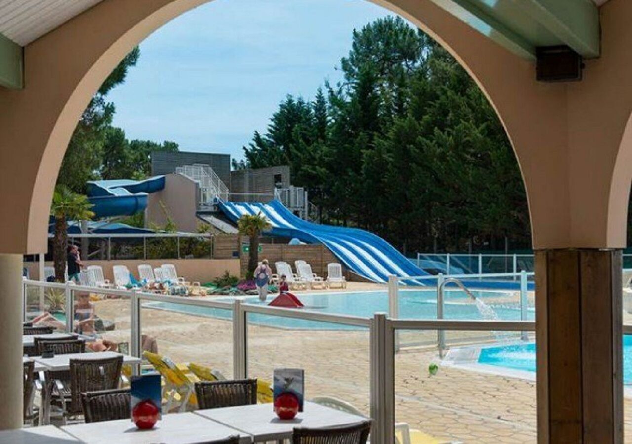 A pool area with a water slide, lounge chairs, and a covered seating area.