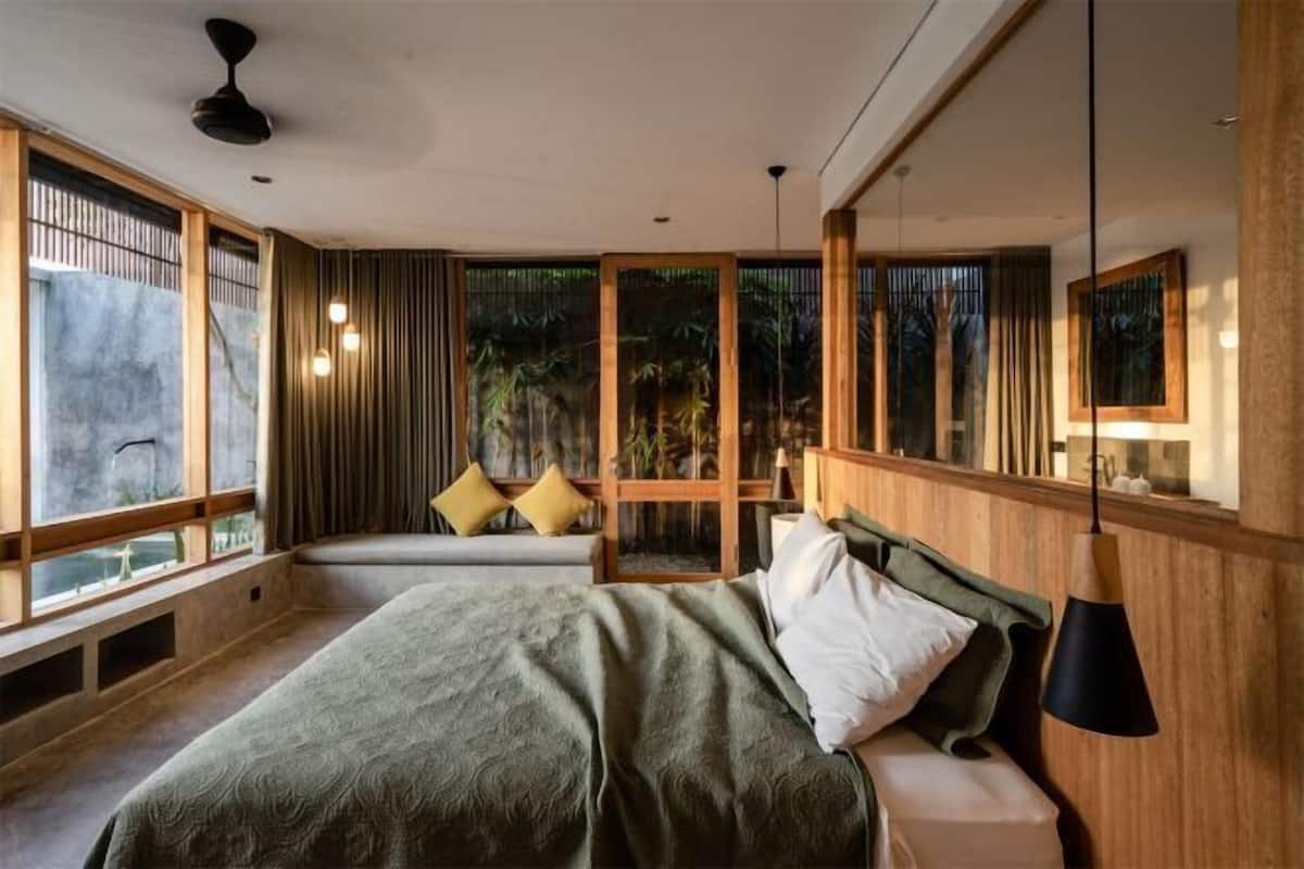 A modern bedroom with a bed, bedside table, and large windows.